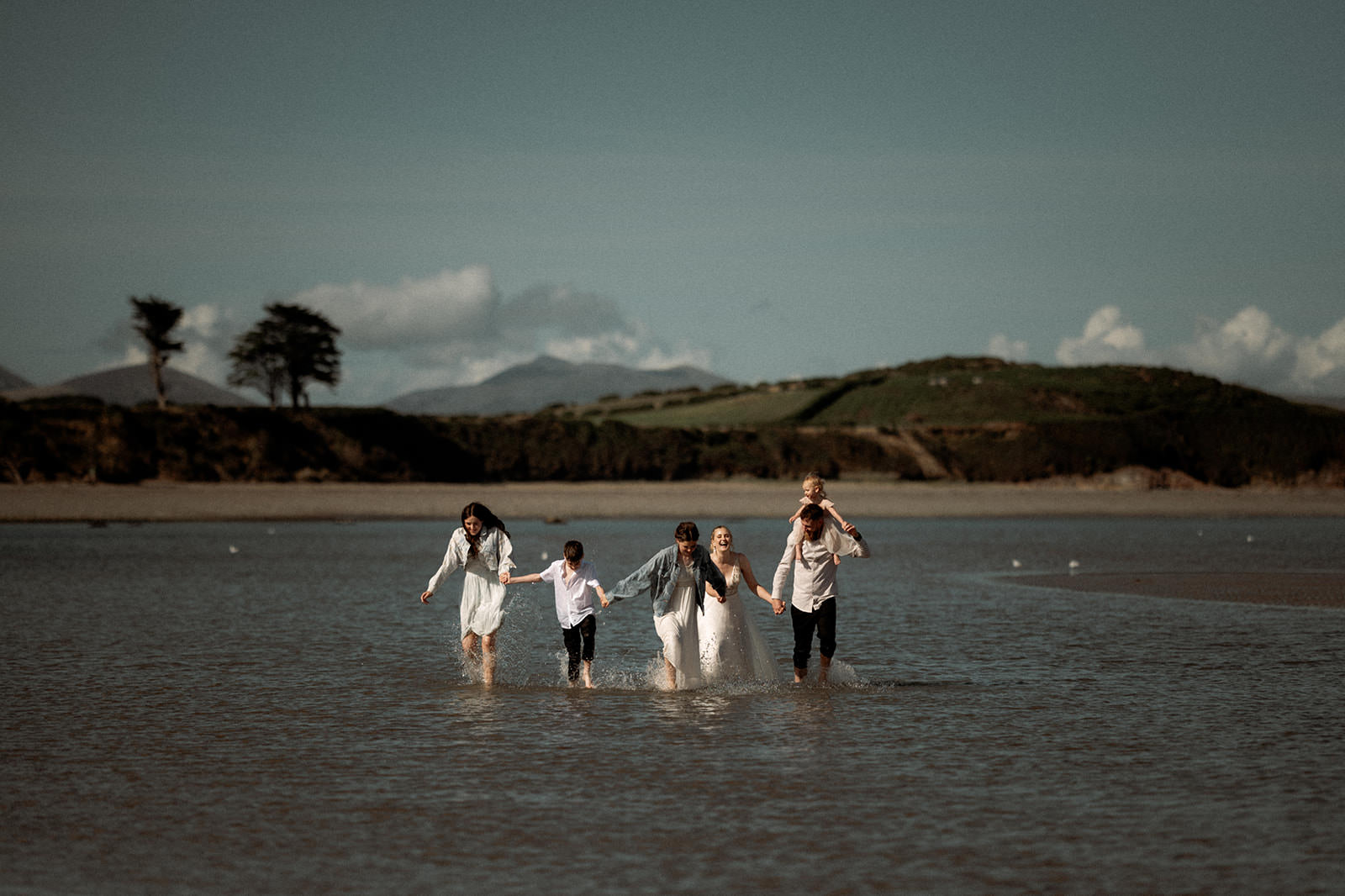 Snowdonia Elopements | a couple on their wedding day in the sea with their children
