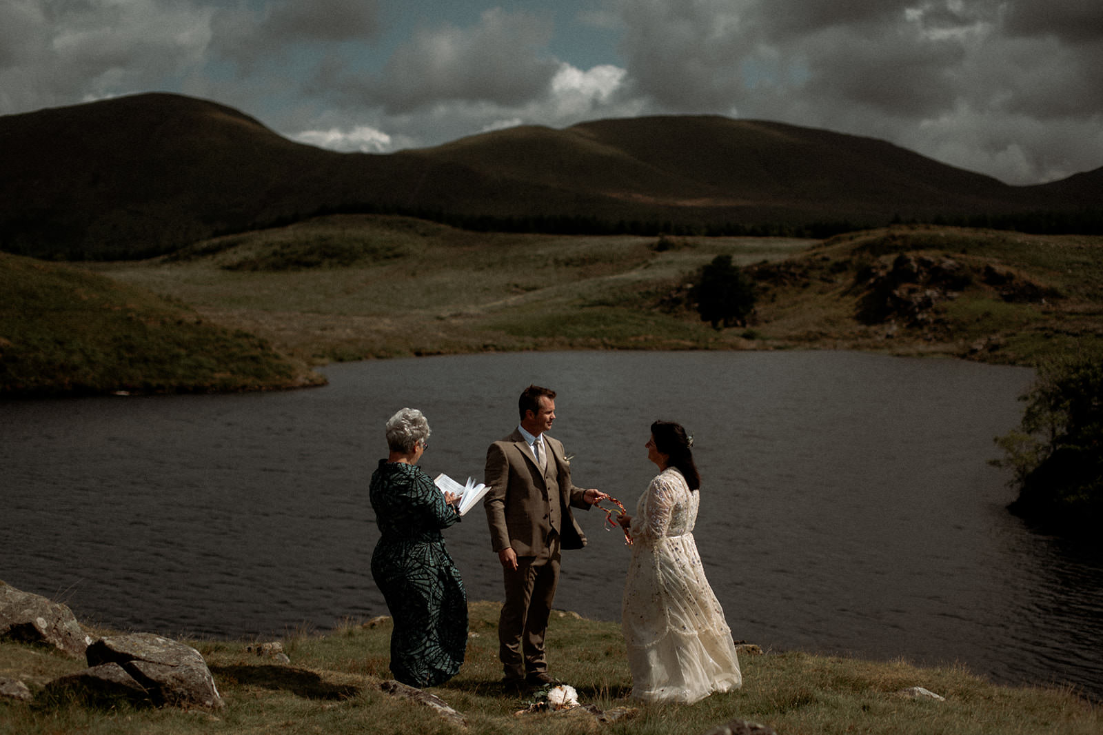 Snowdonia Elopements | couple having a handfasting ceremony with a humanist celebrant overlooking a glacier lake